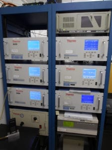 Gas analyzers and a pair of gas dilution calibrators in a typical ambient air monitoring shed. Alicat Whisper flow calibrator pictured at bottom left.