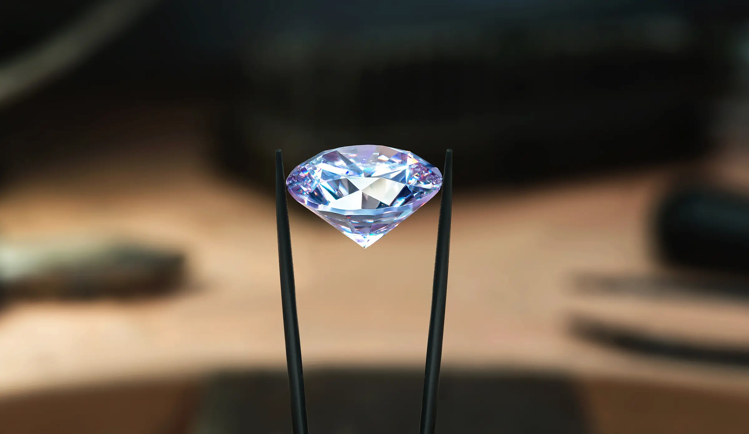 Nahaufnahme eines mit einer Pinzette gehaltenen Diamanten
